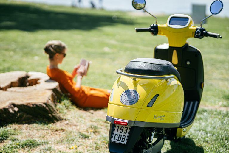 An electric scooter with woman in background reading a book