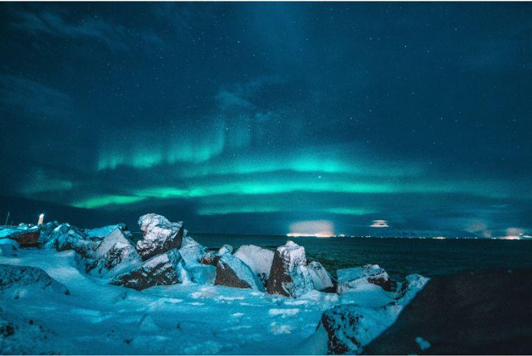 The northern lights over the arctic, where snow and ice are melting because of climate change.