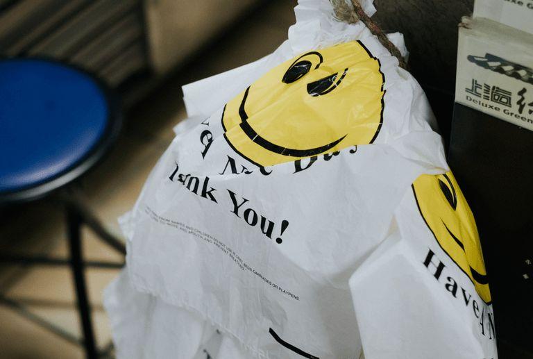 A single-use plastic grocery bag hanging from rope at a grocery store.