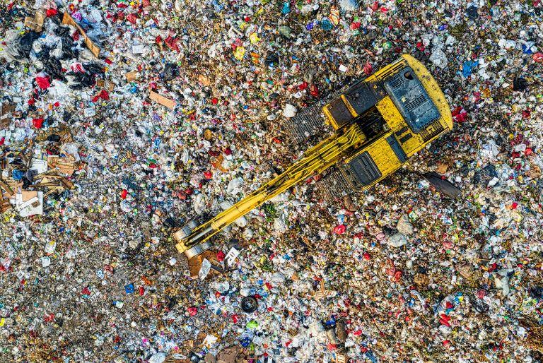 A digger sorts through a landfill where methane is emitted.