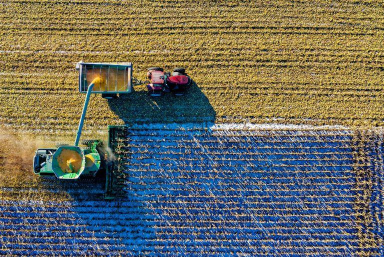 An aerial view of farmer harvesting a crop using a tractor.