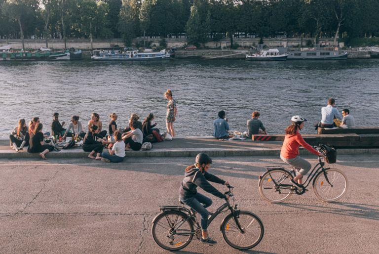 A couple cycling next to a lake for their eco-friendly commute.