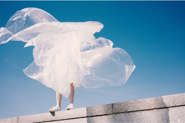 Person holding a large sheet of plastic tarp as the wind blows