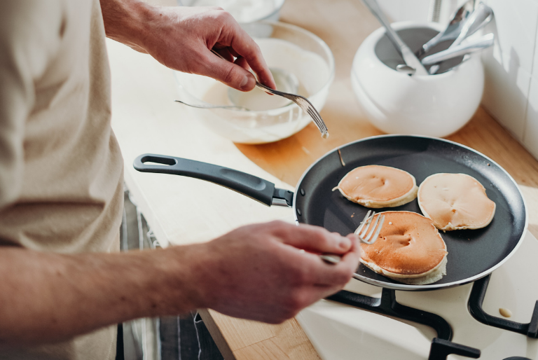 A man cooks pancakes in a frying pan