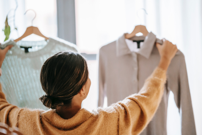 A woman choosing between two shirts in a clothing store