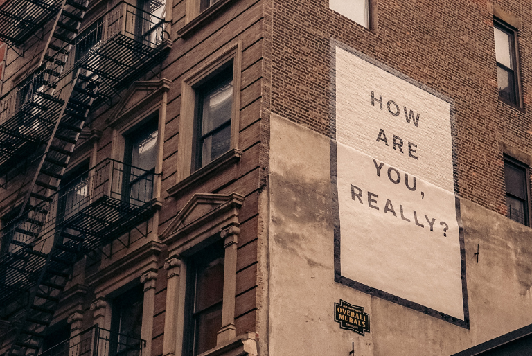 A sign on a building reads How are you, really