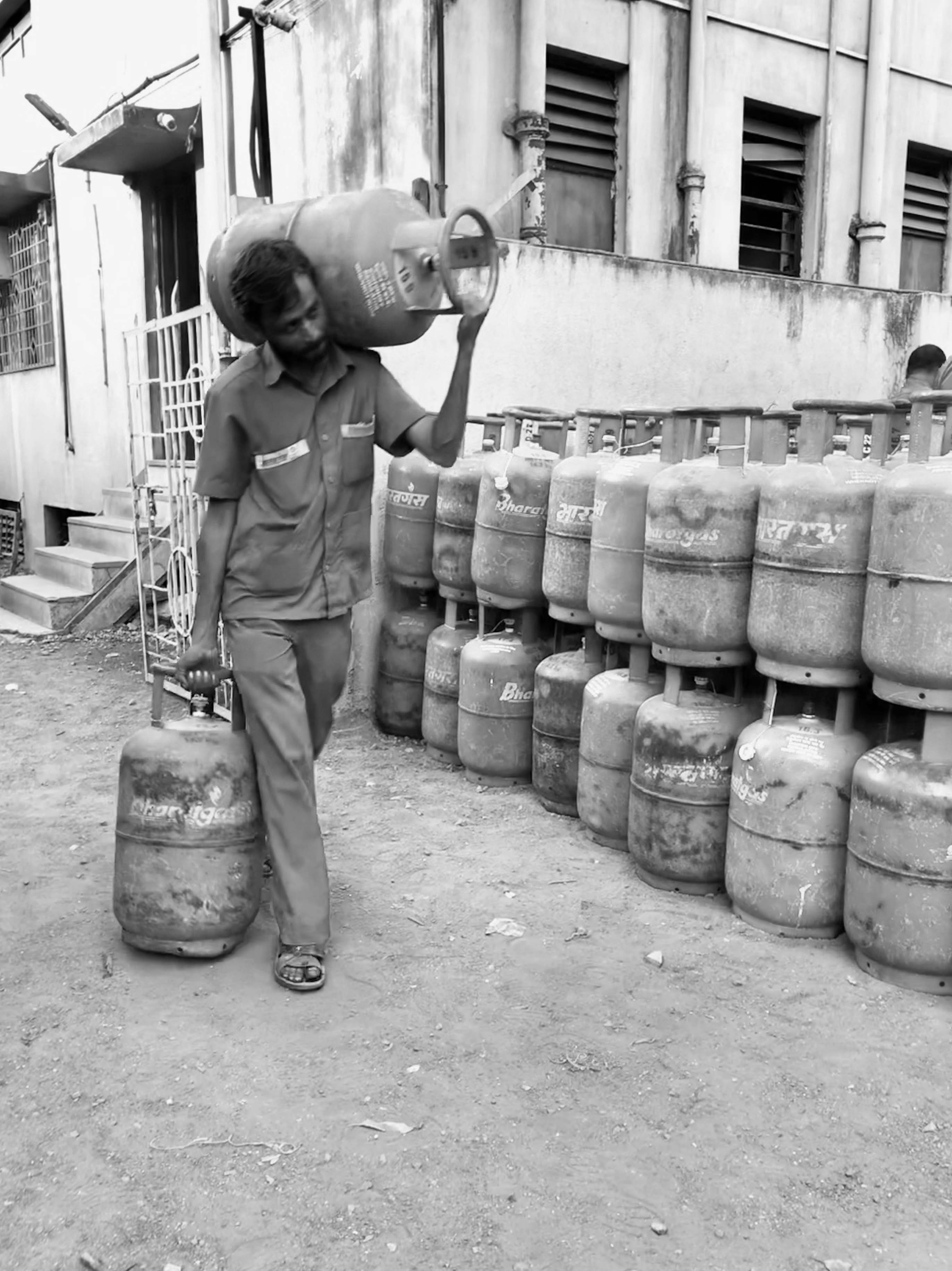 A delivery guy carrying two heavy cylinders with LPG.