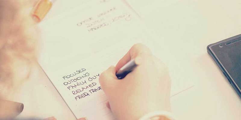 photo: person writing on a persona template pad