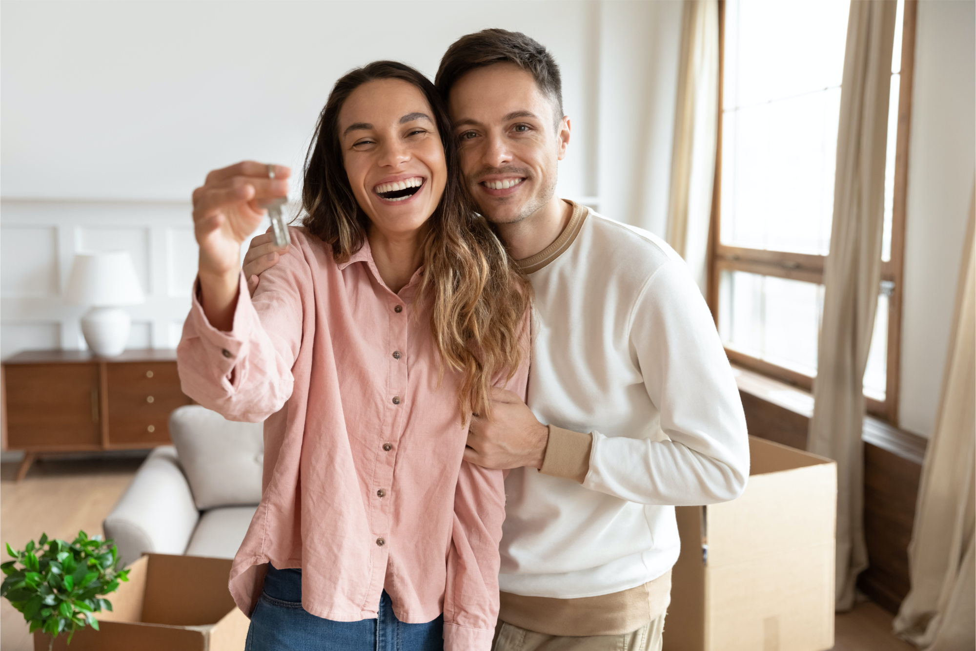 Happy couple smiling holding keys to new home.