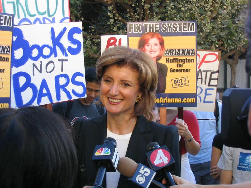 Arianna Huffington stands in front of supporters, talking to news anchors.