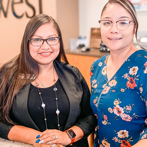 two female SunWest employees smile at their teller stations at the Peoria branch location