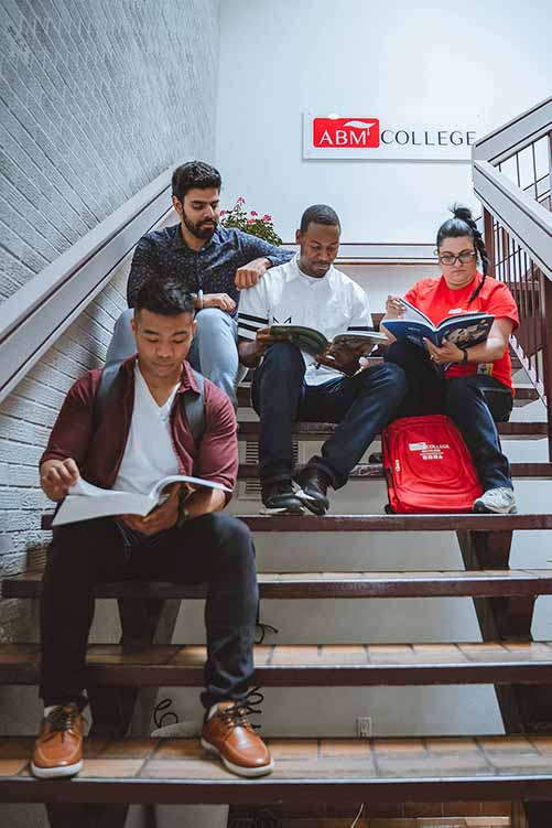 ABM College students sitting on the campus stairs.