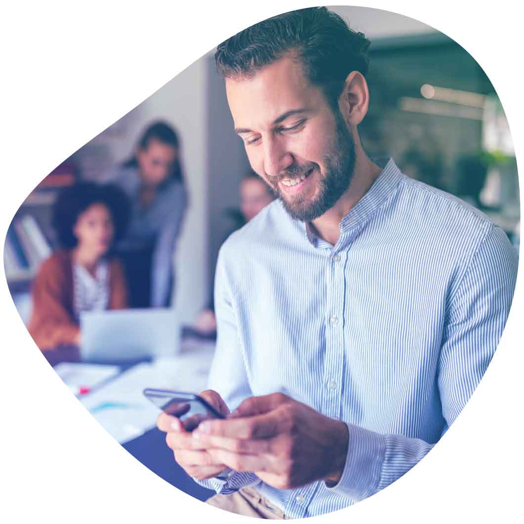 Ein zufriedener Mitarbeiter schaut auf sein Smartphone und freut sich über digitale HR Services von Haufe
