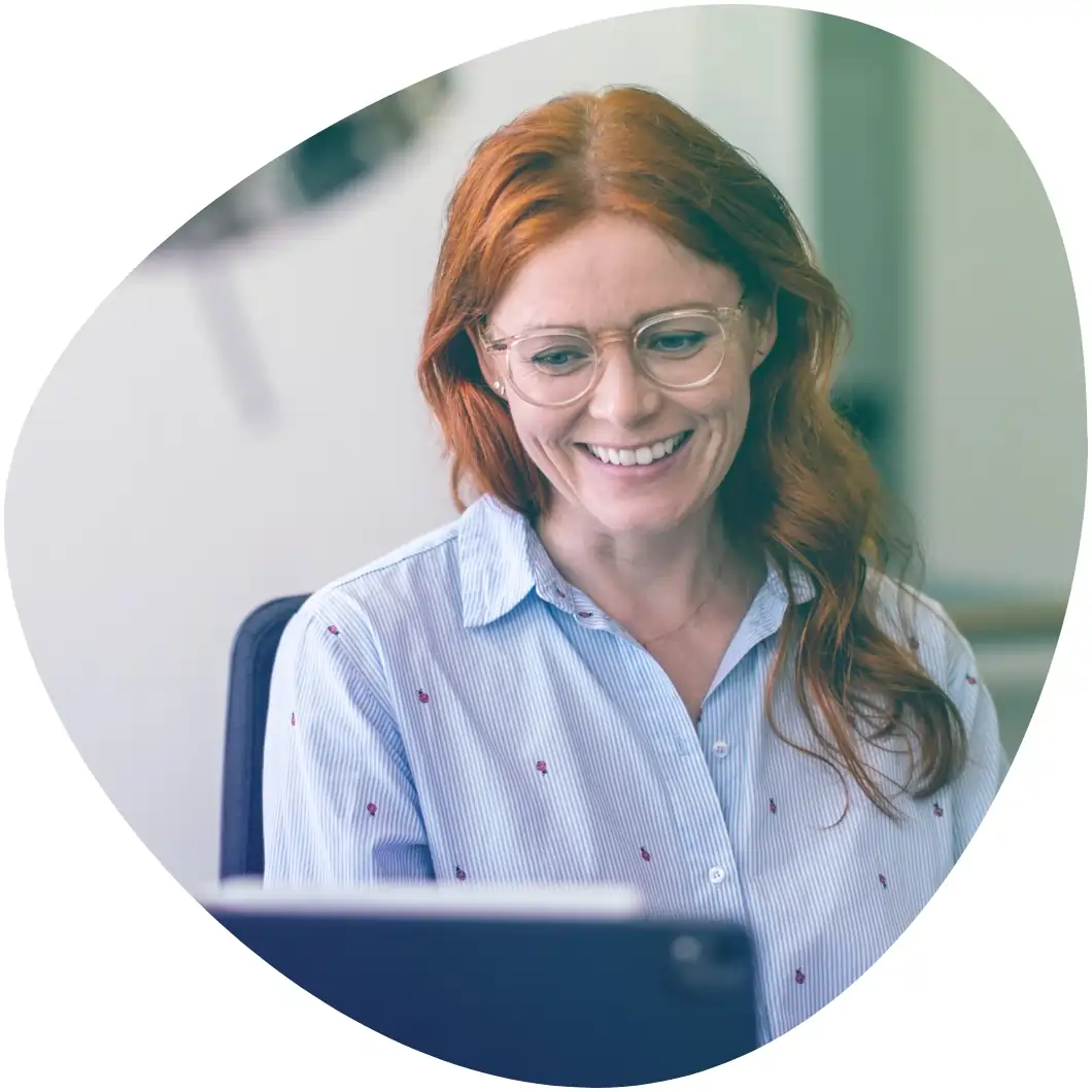 Bild von einer Frau, die am Laptop mit der digitalen Personalakte von Haufe arbeitet und dabei sehr zufrieden lächelt.