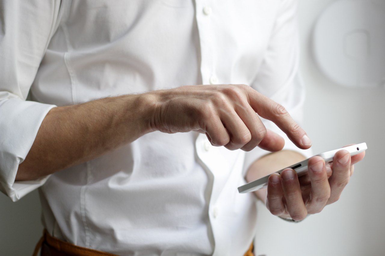 A man in an oxford shirt sends a text message.