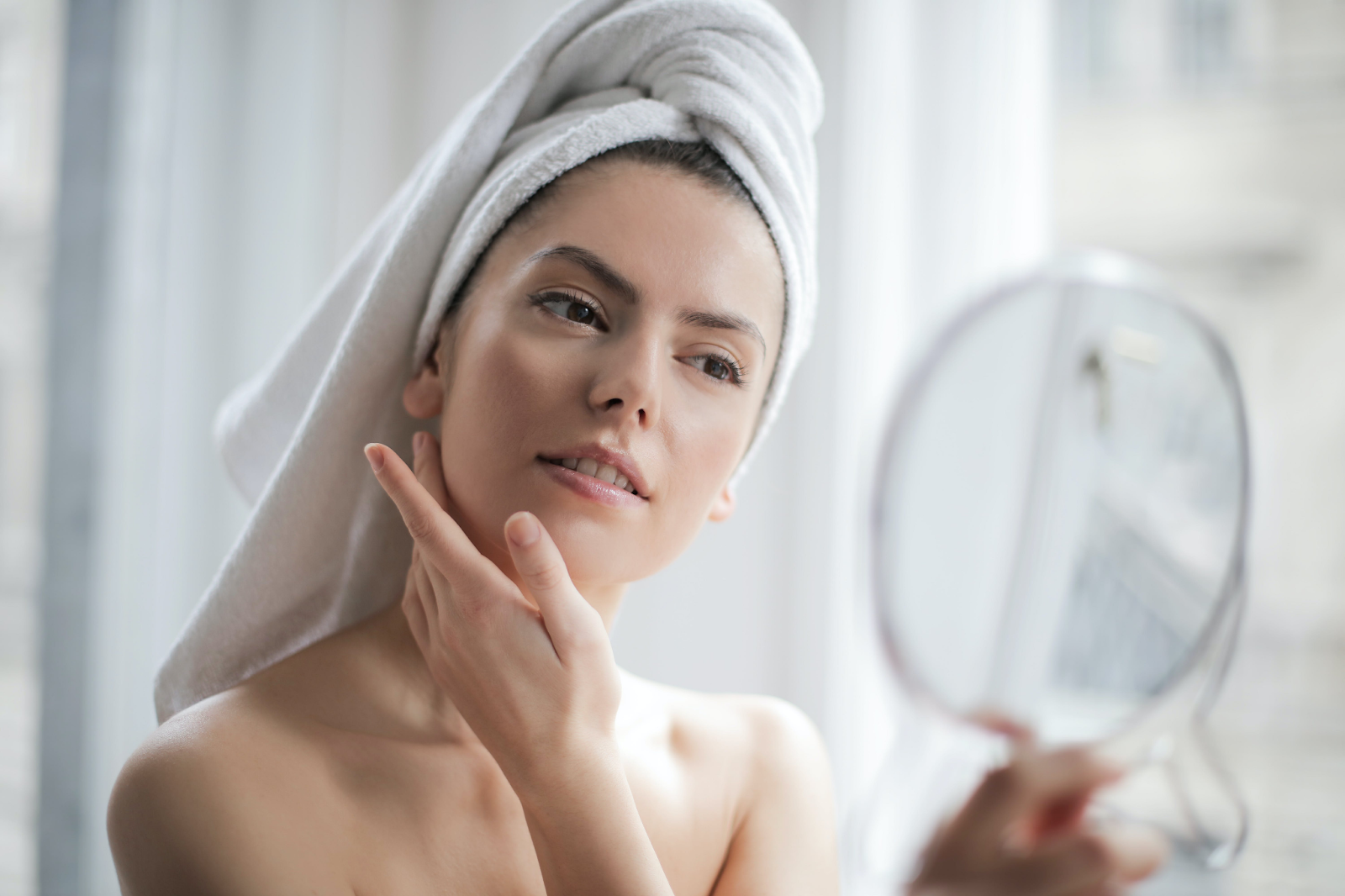 woman putting cream on her face in the bathroom