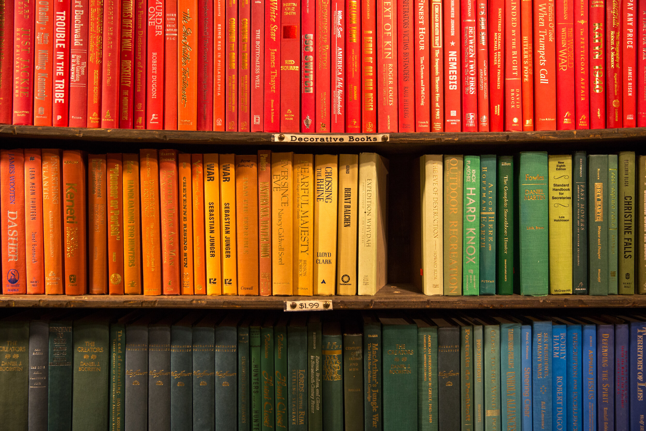 By Color This is perhaps one of the best ways to organize your books if you are looking to create a visual statement, though it can be one of the most exhausting to pull off. To effectively organize your bookshelf based on color, I recommend splitting books into color categories based on the color of their spine. Once you have your books paired into colors, take it a step further and group the books in that color category based on how dark or light the coloring is. After you have divided the books into your color groups, display them on your shelves in descending order so that it creates kind of an ombre look. If you want your shelves to truly make an impact in your home decor, this is absolutely the way to display them! However, it should be mentioned that if you elect to go the color organization route that you cannot choose to simultaneously organize them with a second method such as alphabetization. This will ruin how the colored spines are displayed. And though this might seem like it would be a hard way to go back and find an old book to read, if you can remember the cover, things are usually pretty easy to find! Plus, this organization method makes your shelves totally Instagrammable! 
