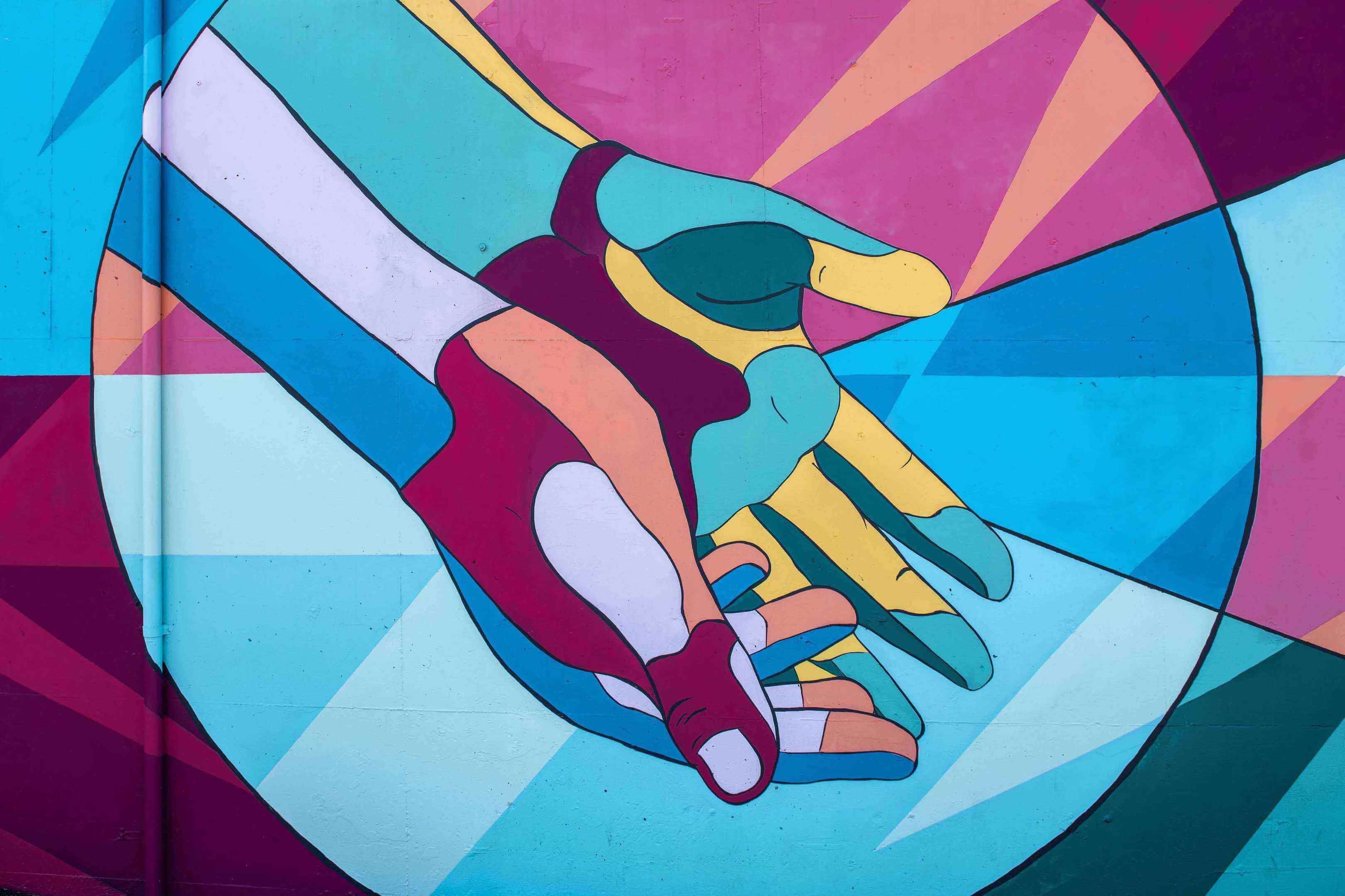 An colorful painted mural of two hands outstretched
