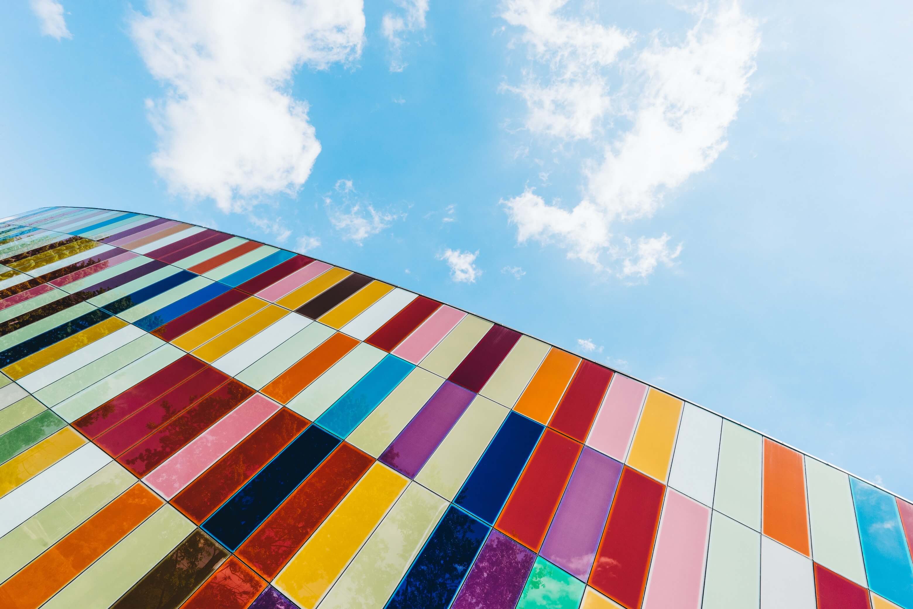 Blue sky behind a building with many colorful, rectangular tiles