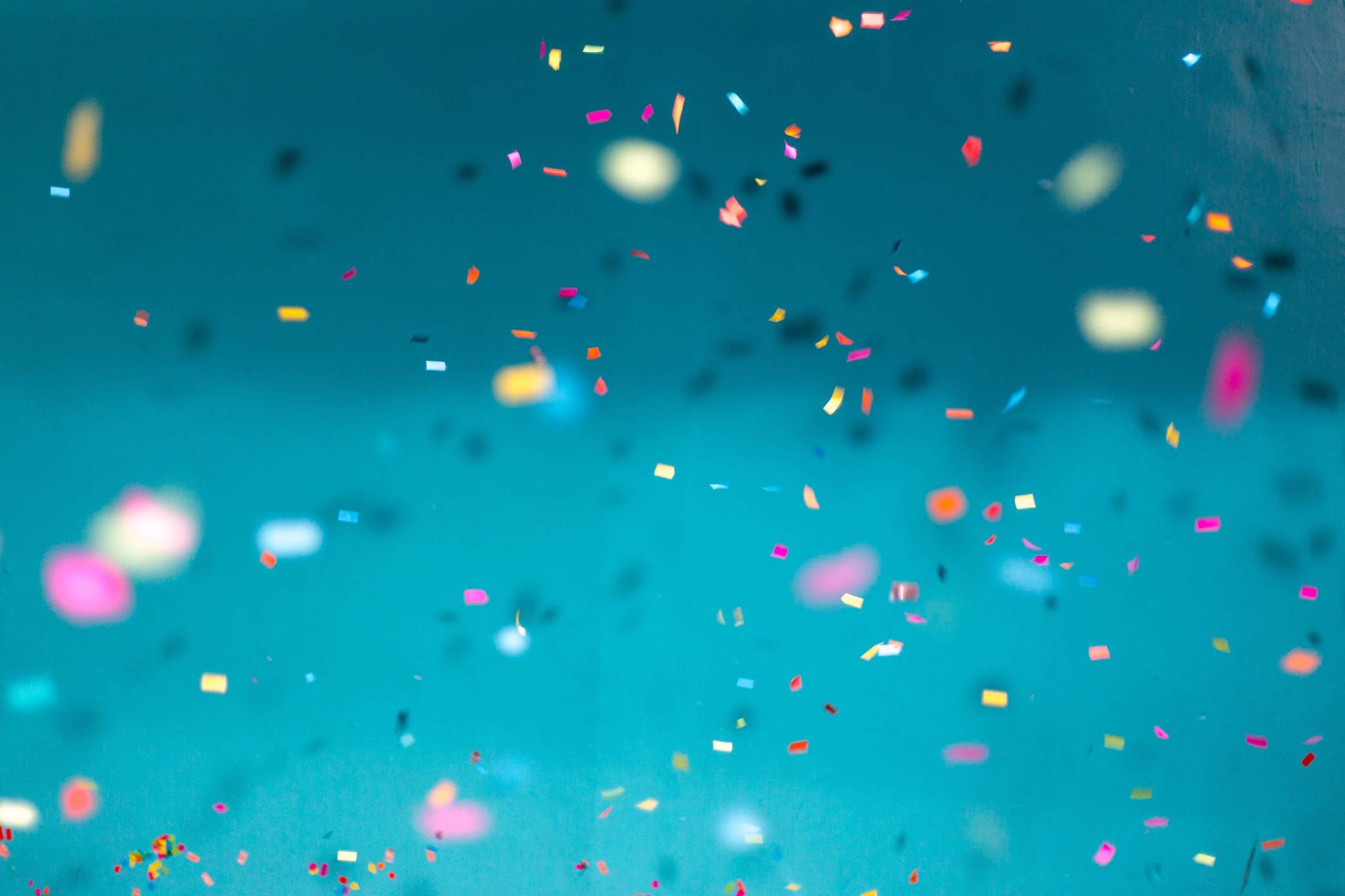 Colorful confetti falling against a teal backdrop