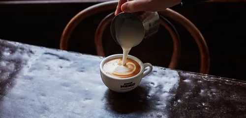 A latte being poured into a mug