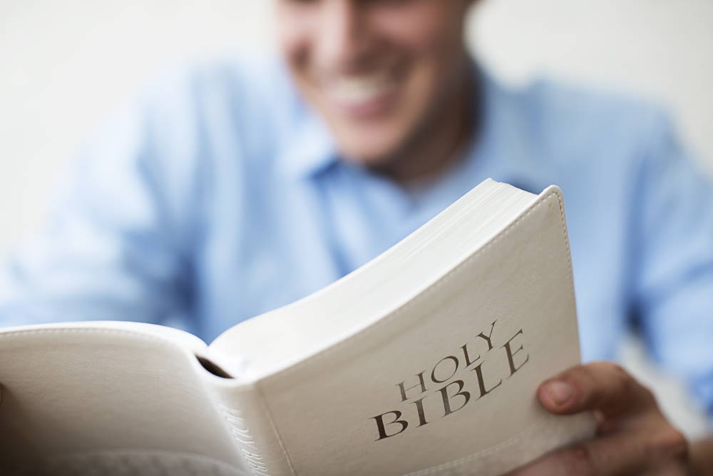 A man smiling while reading the Bible