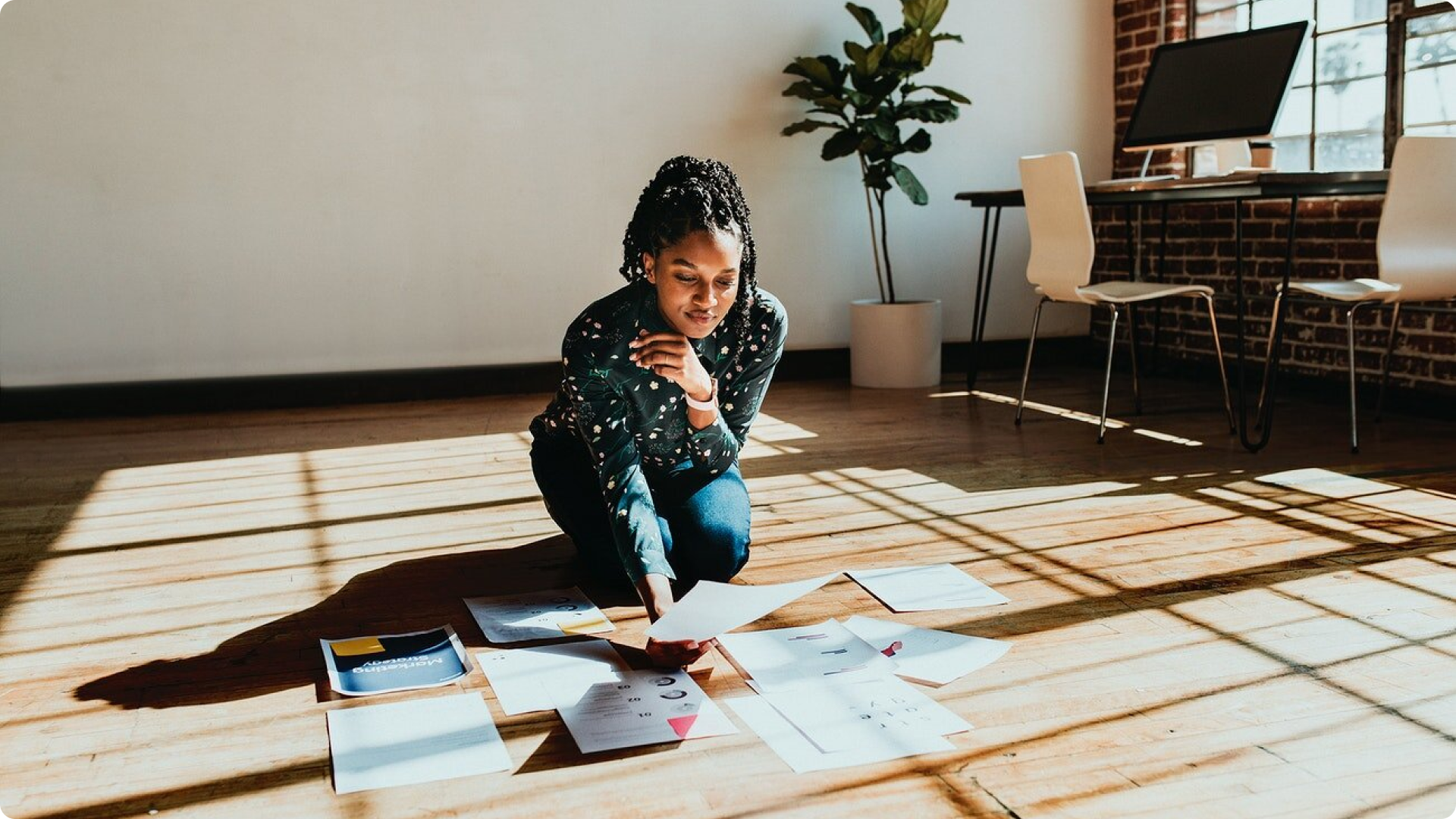 Woman looking at work and design papers on the floor in a well-lit office