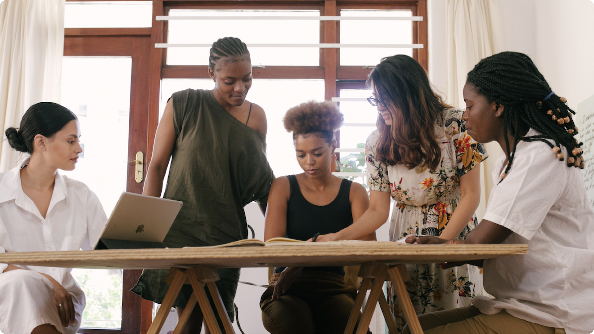 A diverse set of woman collaborating on a UX project at a table