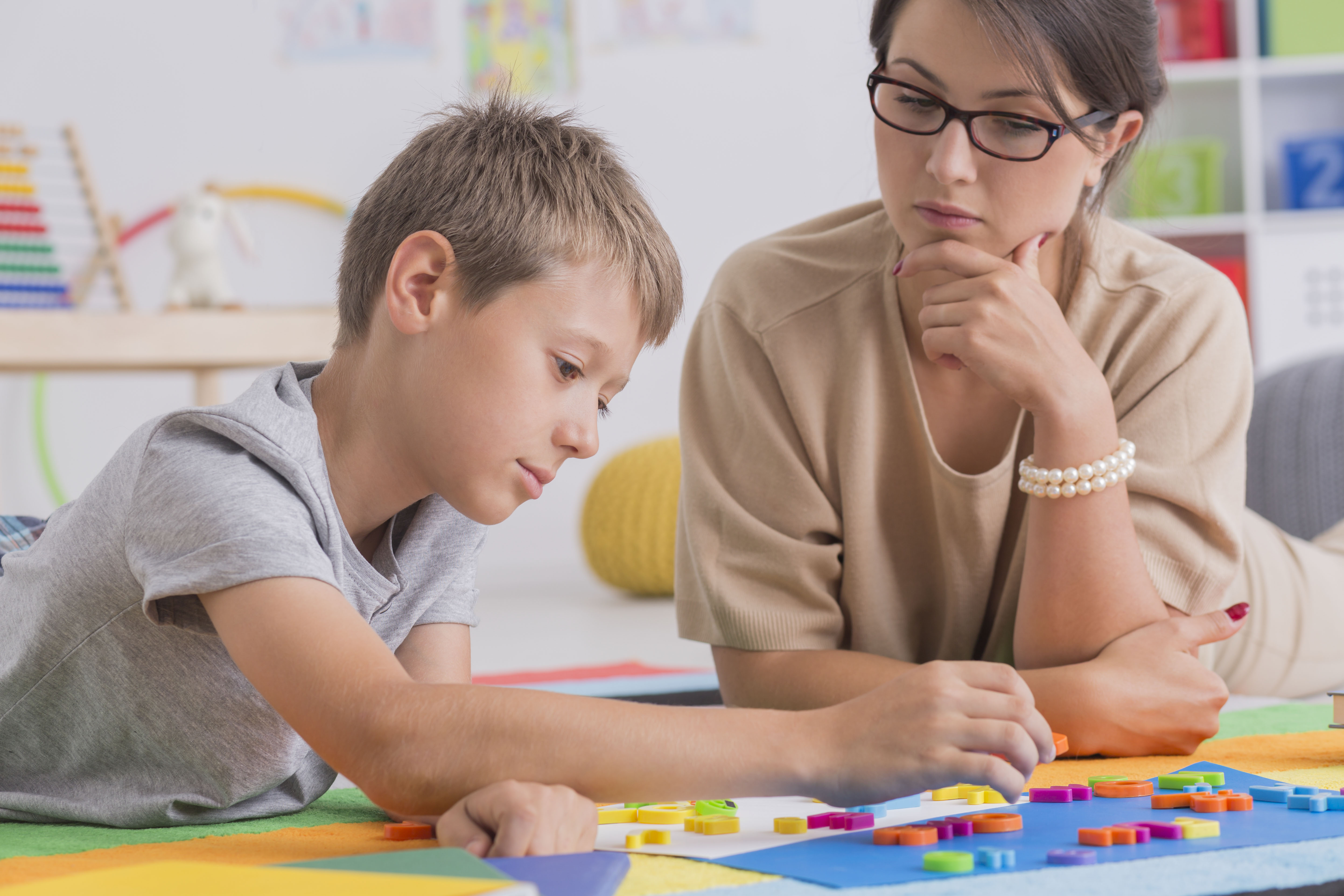 Young boy drawing with woman watching