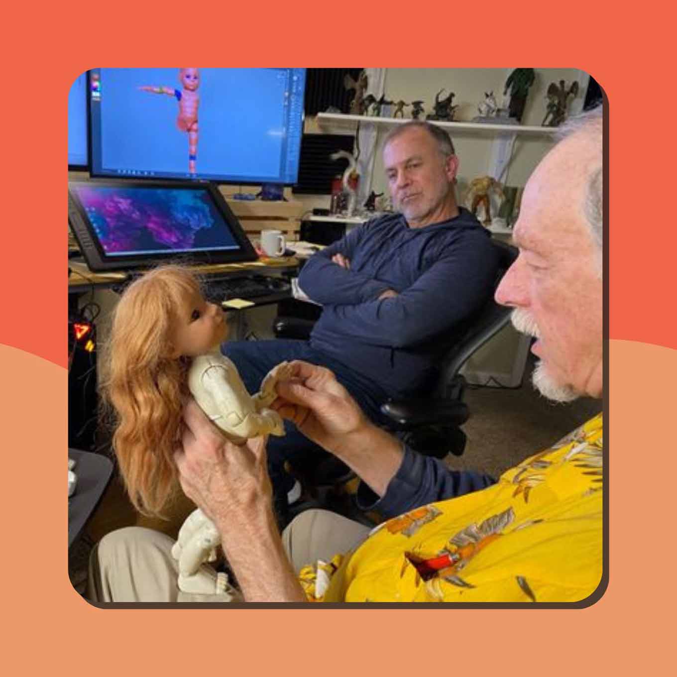 Two men work on a 3D doll design in front of a computer monitor