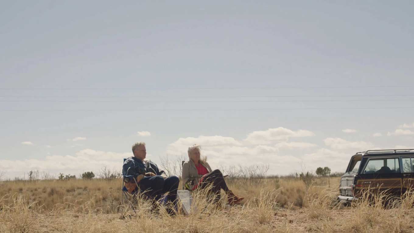 A still from "Will & Harper" featuring Will Farrell and Harper Steele sitting in a wide open plain