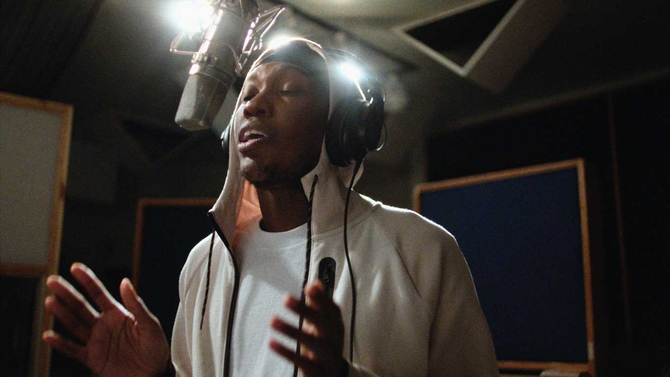 A still from "As We Speak" of rapper Kemba in a recording booth