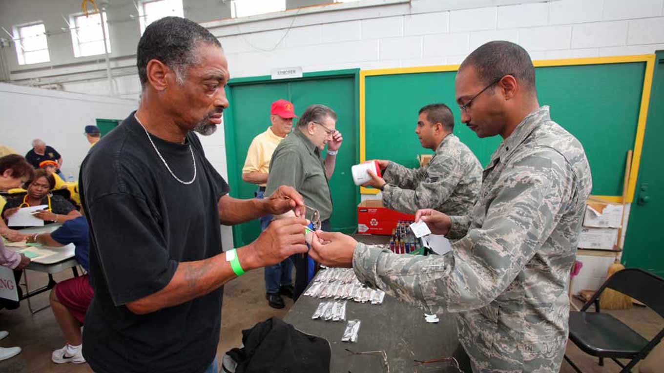 Public Health Officer 1st Lt. Gyasi J. Mann, right, and Bioenvironmental Engineer Senior Airman Emilio D. Gonzalez, second from right, help homeless veterans choose a pair of reading glasses during Stand Down 2012 at the National Guard Armory in Cherry Hill