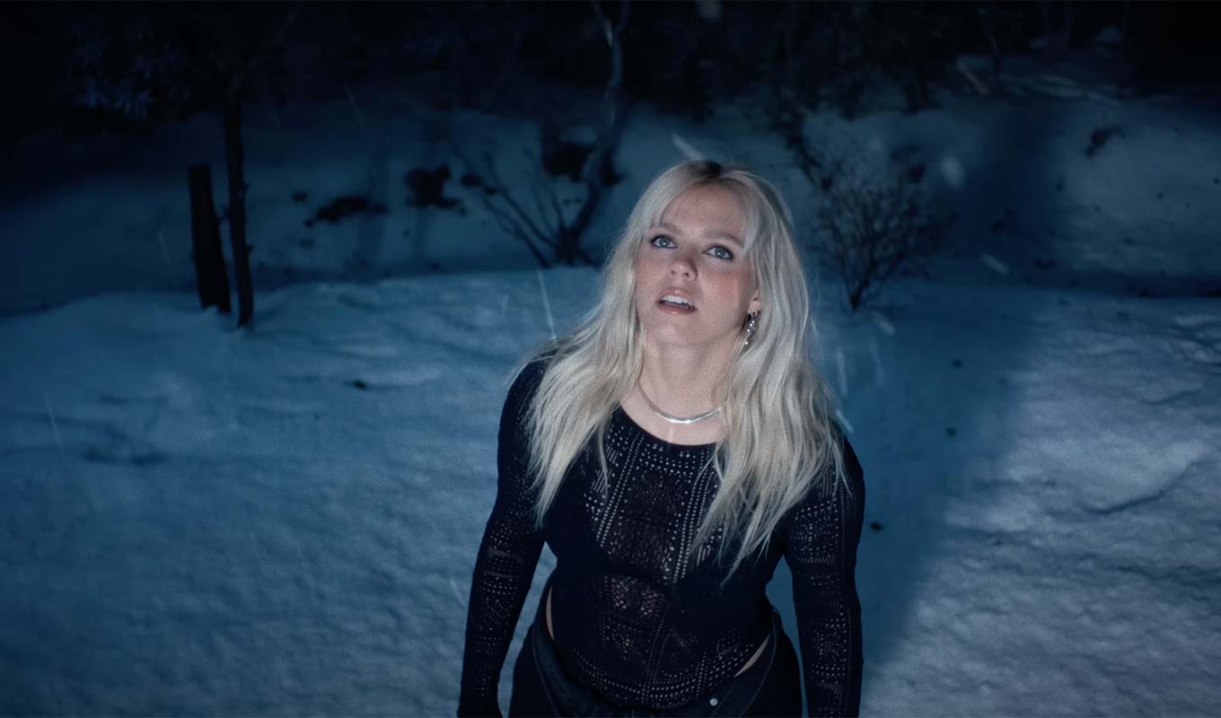 Renee Rapp stands in the snow, looking up, in the "Snow Angel" music video