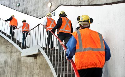 Workers wearing safety equipment ascending a staircase in a hydropower station