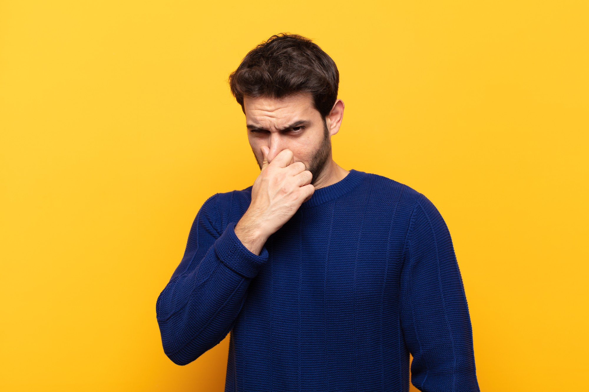 Man holding nose and grimacing