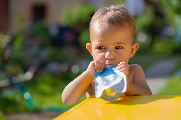 Little boy sucking on yoghurt pouch
