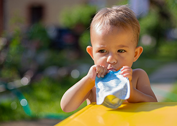Little boy sucking on yoghurt pouch