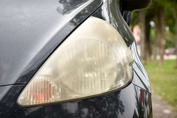 close up of dull headlight on dark sedan
