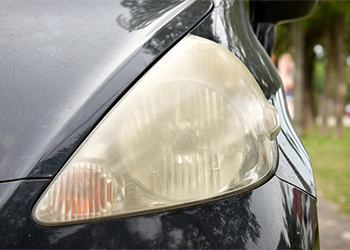 close up of dull headlight on dark sedan