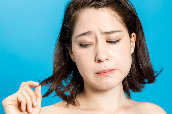 young woman looking worried at the ends of her hair