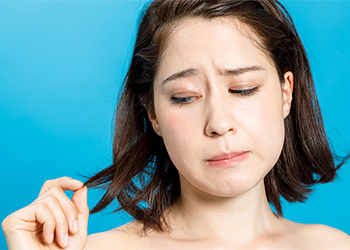 young woman looking worried at the ends of her hair