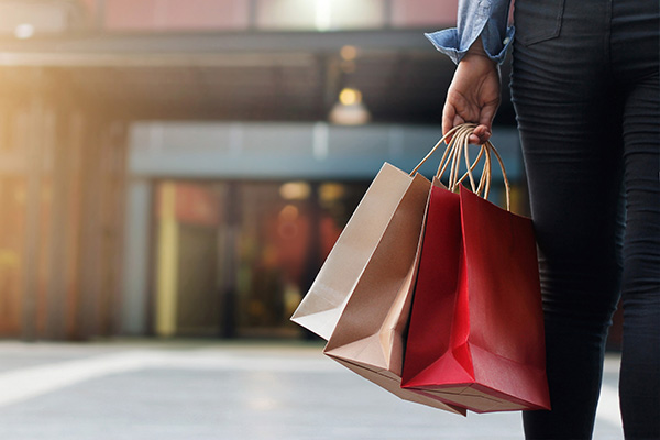 Woman walking in shopping mall holding multiple shopping bags