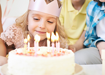 Young girl blowing out candles on a birthday cake