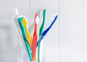Toothbrushes and toothpaste on bathroom shelf