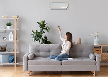 Woman in cosy home adjusting air conditioner