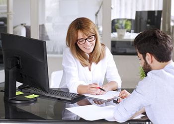 Man and woman at a desk with a computer - Real Profit Business Solutions - Bookkeeping