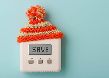 Digital thermostat wearing a red and yellow striped woolly hat