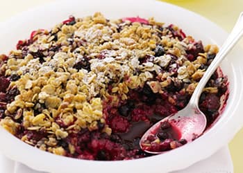 A dish of berry crumble with a spoon