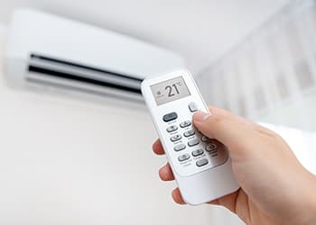 Hand holding an air conditioner remote control